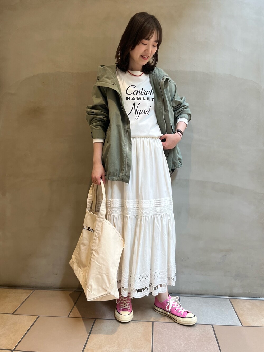 グリーン系のマウンテンパーカー、ホワイト系のTシャツ/カットソー、ホワイト系のトートバッグを着用したレディースの春コーディネートの5枚目の写真