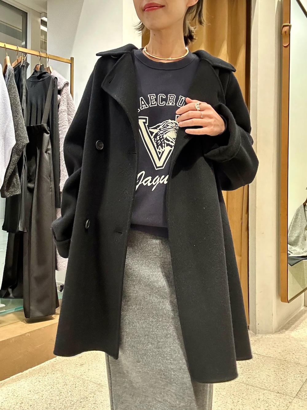 グレー系のスカート、ブルー系のスウェット、ブラック系のピーコートを着用したレディースの秋コーディネートの7枚目の写真