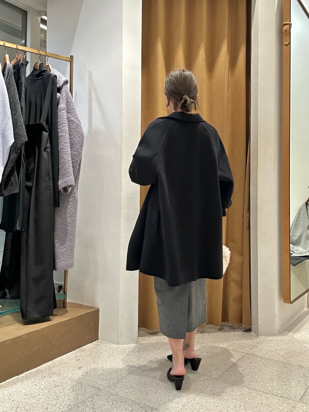 グレー系のスカート、ブルー系のスウェット、ブラック系のピーコートを着用したレディースの秋コーディネートの3枚目の写真