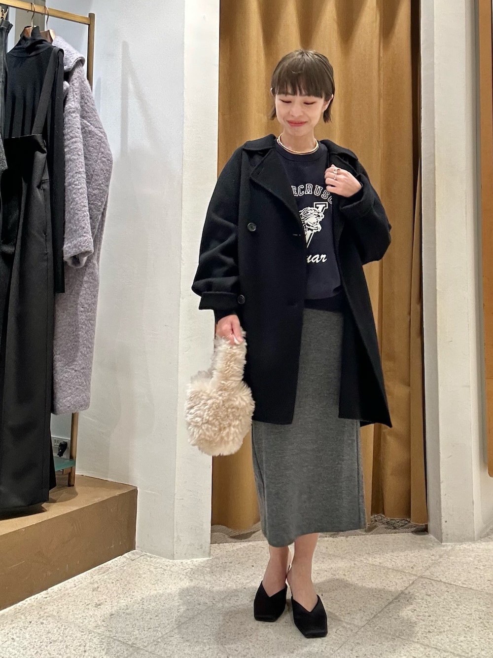 グレー系のスカート、ブルー系のスウェット、ブラック系のピーコートを着用したレディースの秋コーディネートの4枚目の写真