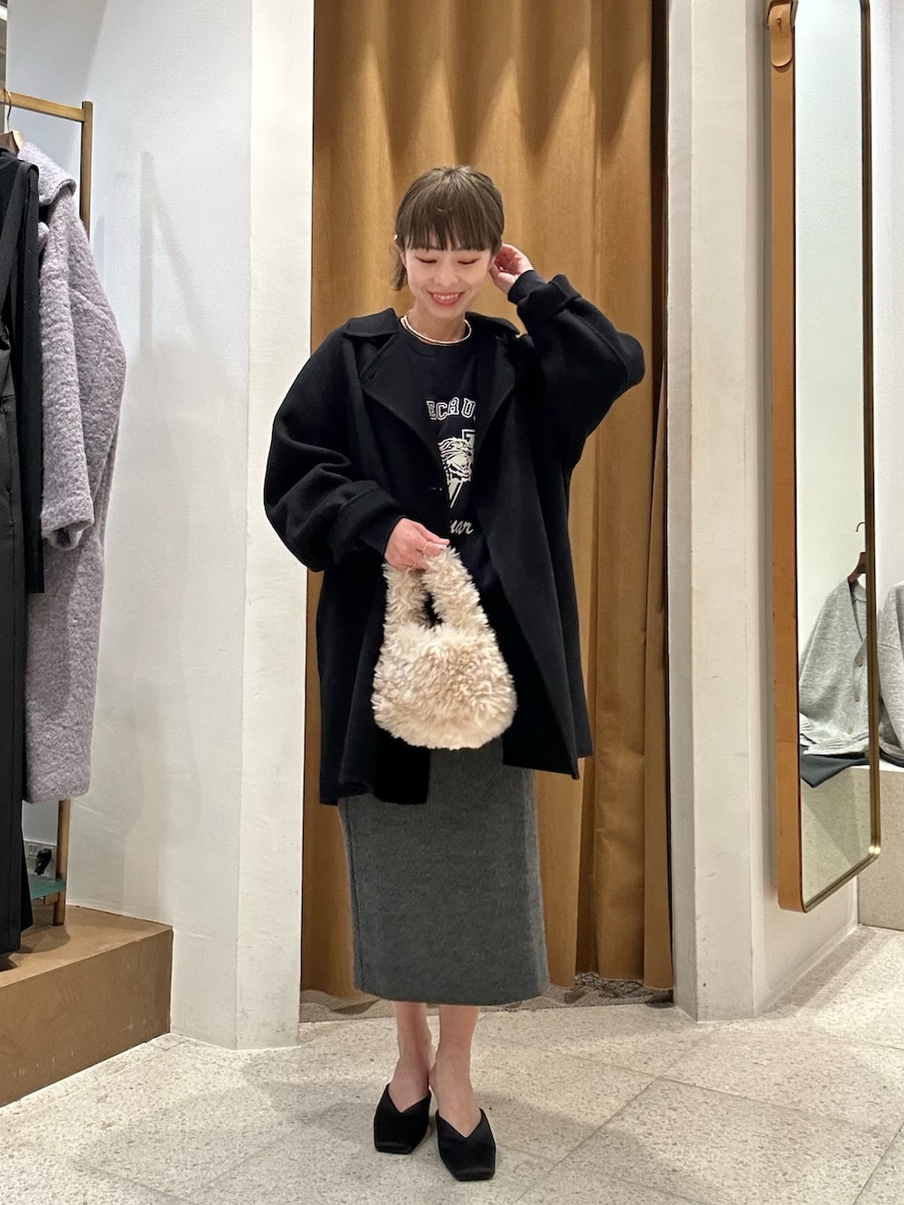 グレー系のスカート、ブルー系のスウェット、ブラック系のピーコートを着用したレディースの秋コーディネートの6枚目の写真