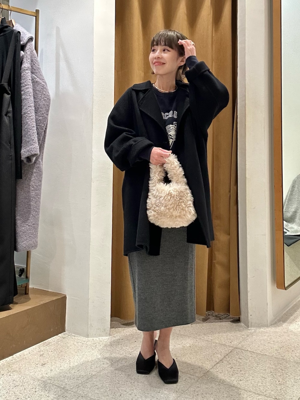 グレー系のスカート、ブルー系のスウェット、ブラック系のピーコートを着用したレディースの秋コーディネートの5枚目の写真