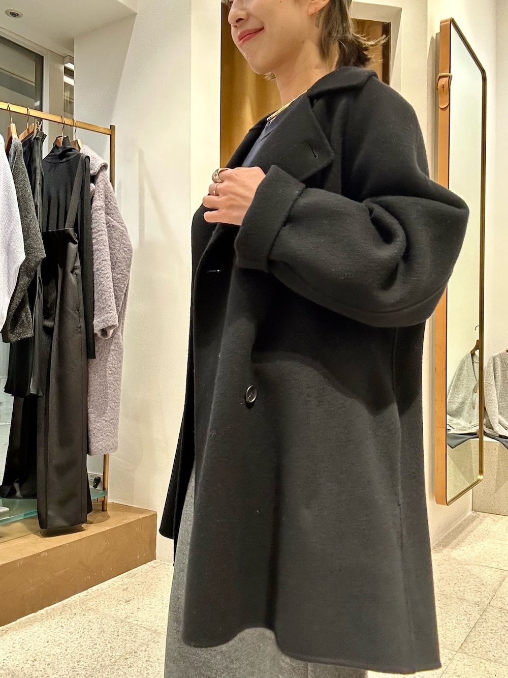 グレー系のスカート、ブルー系のスウェット、ブラック系のピーコートを着用したレディースの秋コーディネートの8枚目の写真