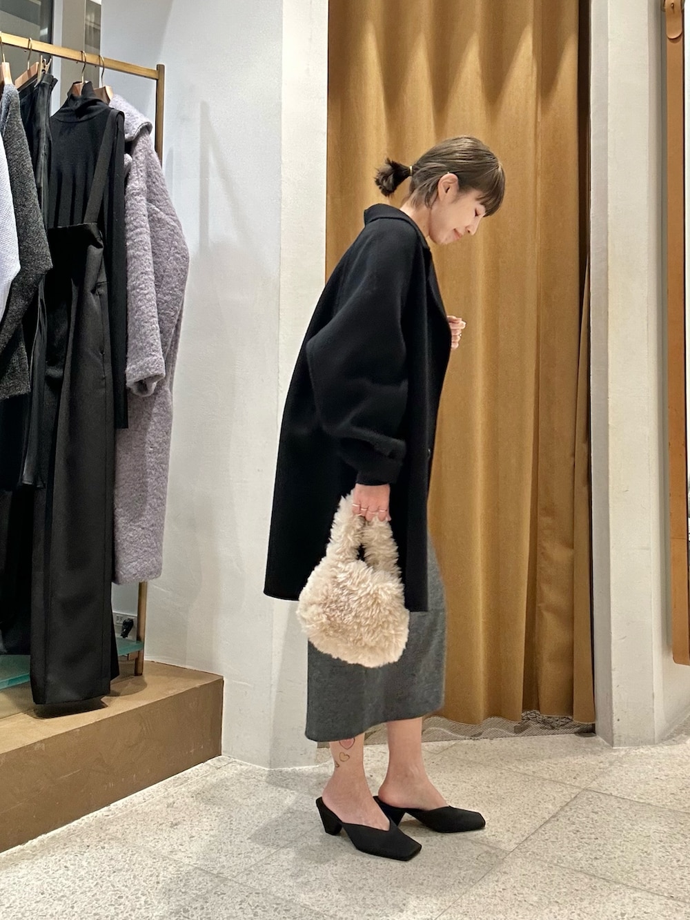 グレー系のスカート、ブルー系のスウェット、ブラック系のピーコートを着用したレディースの秋コーディネートの2枚目の写真