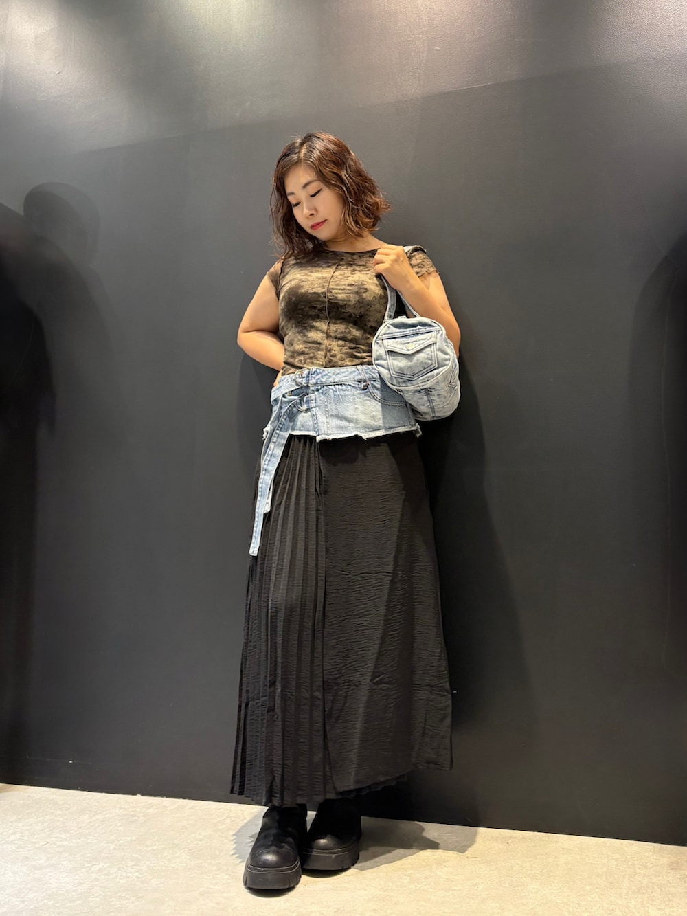ブルー系のデニムスカート、ブラック系のTシャツ/カットソー、ブルー系のハンドバッグを着用したレディースの夏コーディネートの2枚目の写真