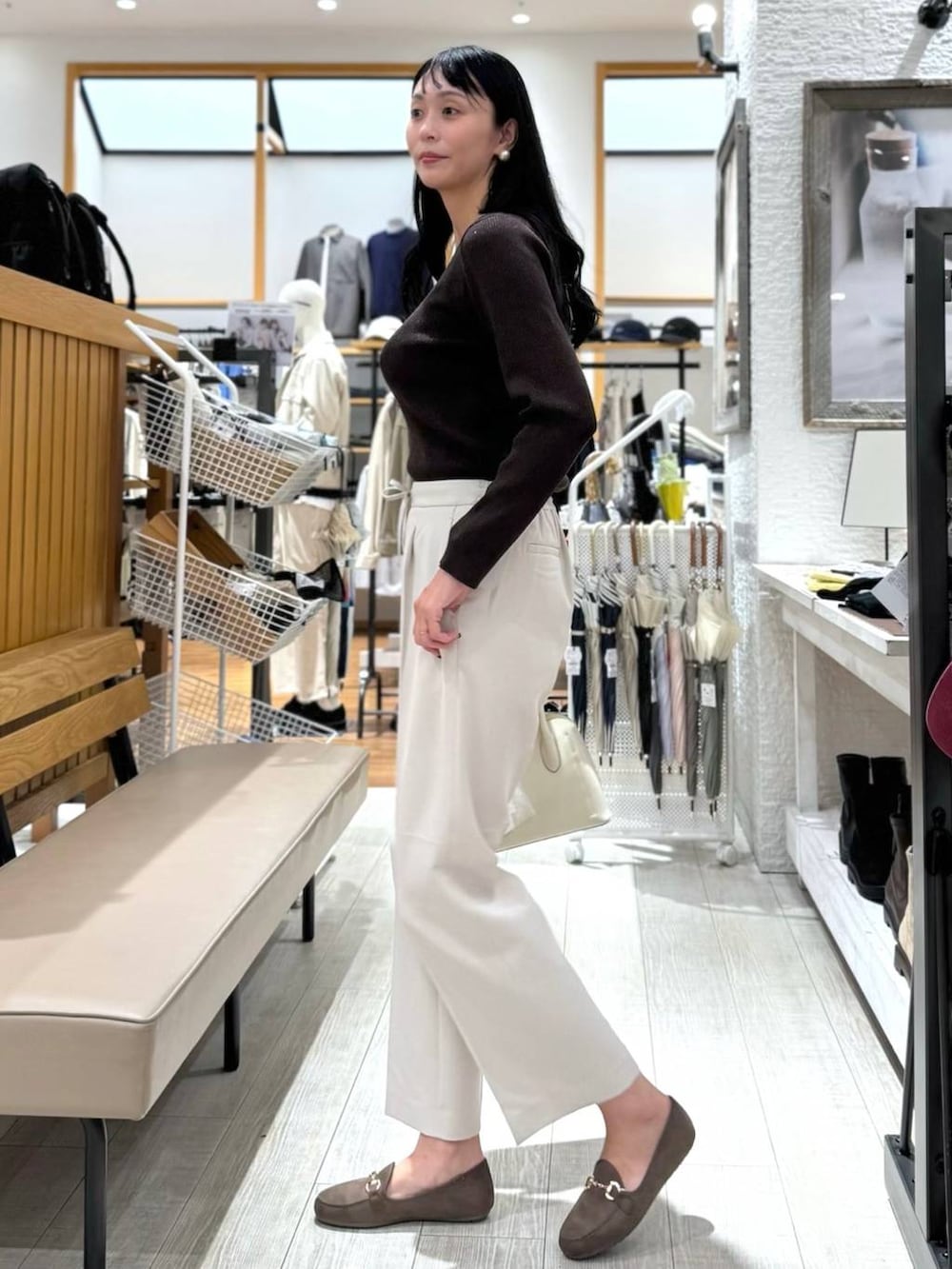 ホワイト系のショルダーバッグ、ベージュ系のスラックス、ブラウン系のニット/セーターを着用したレディースの秋コーディネートの3枚目の写真