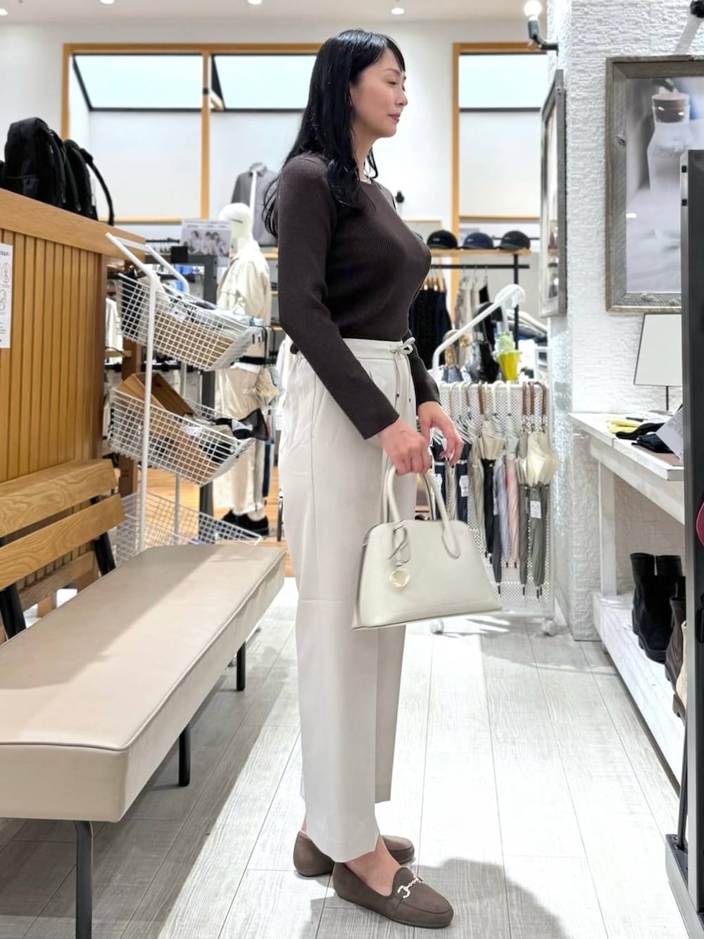 ホワイト系のショルダーバッグ、ベージュ系のスラックス、ブラウン系のニット/セーターを着用したレディースの秋コーディネートの5枚目の写真