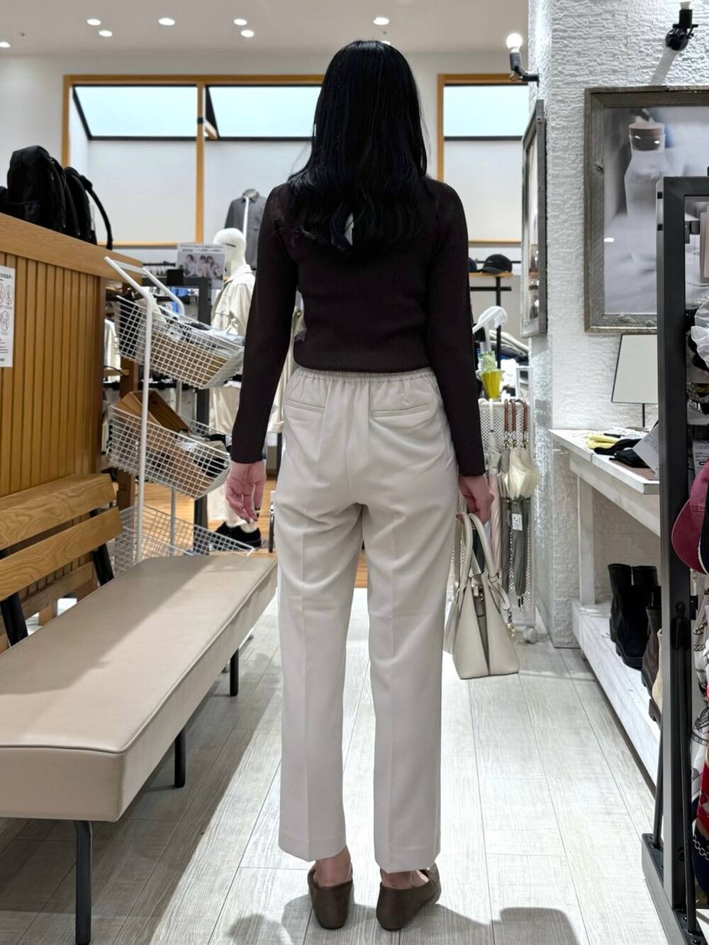 ホワイト系のショルダーバッグ、ベージュ系のスラックス、ブラウン系のニット/セーターを着用したレディースの秋コーディネートの4枚目の写真