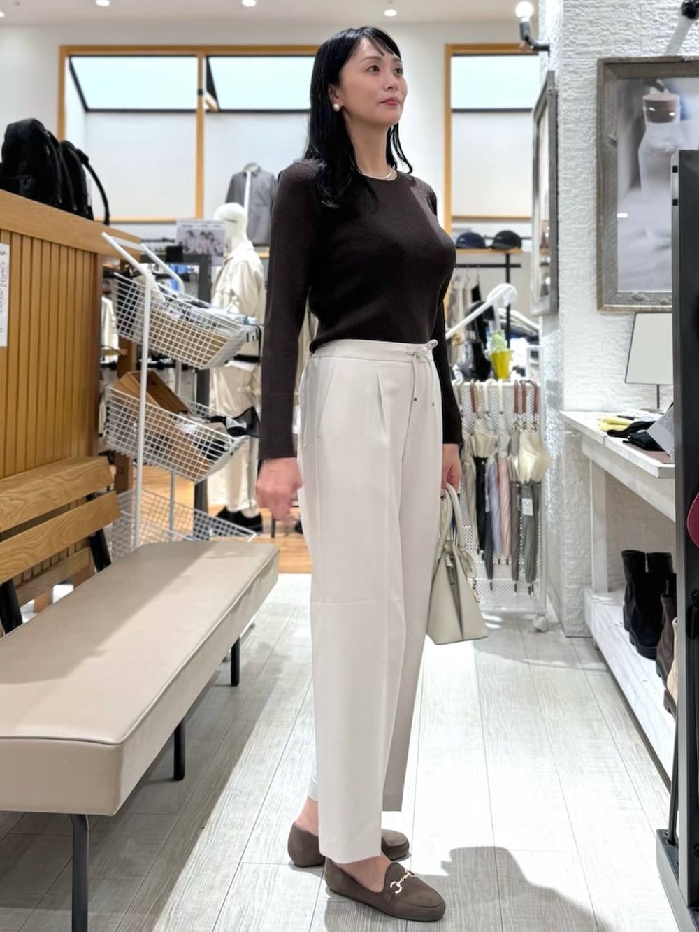 ホワイト系のショルダーバッグ、ベージュ系のスラックス、ブラウン系のニット/セーターを着用したレディースの秋コーディネートの6枚目の写真