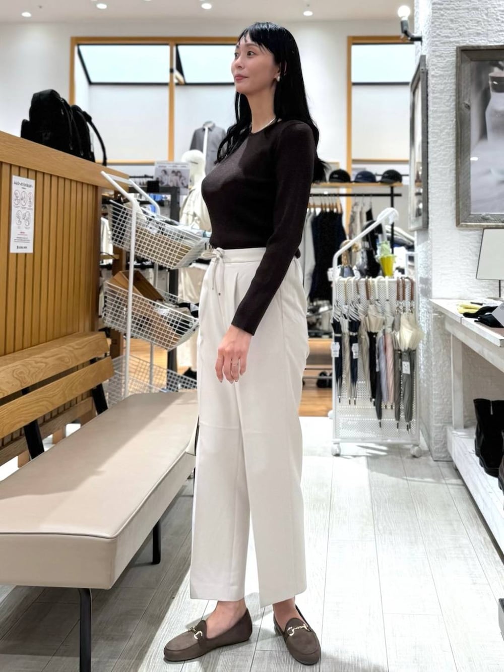 ホワイト系のショルダーバッグ、ベージュ系のスラックス、ブラウン系のニット/セーターを着用したレディースの秋コーディネートの2枚目の写真