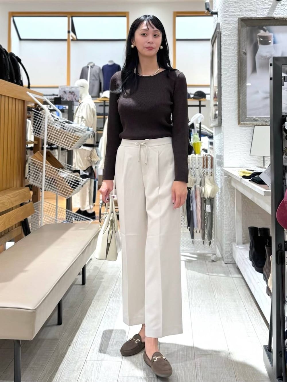 ホワイト系のショルダーバッグ、ベージュ系のスラックス、ブラウン系のニット/セーターを着用したレディースの秋コーディネートの7枚目の写真