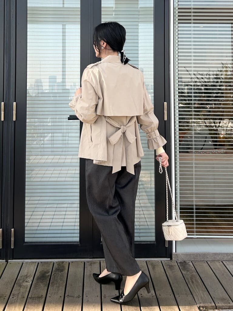 ベージュ系のトレンチコート、イエロー系のニット/セーター、ブラック系のその他パンツを着用したレディースの春コーディネートの3枚目の写真