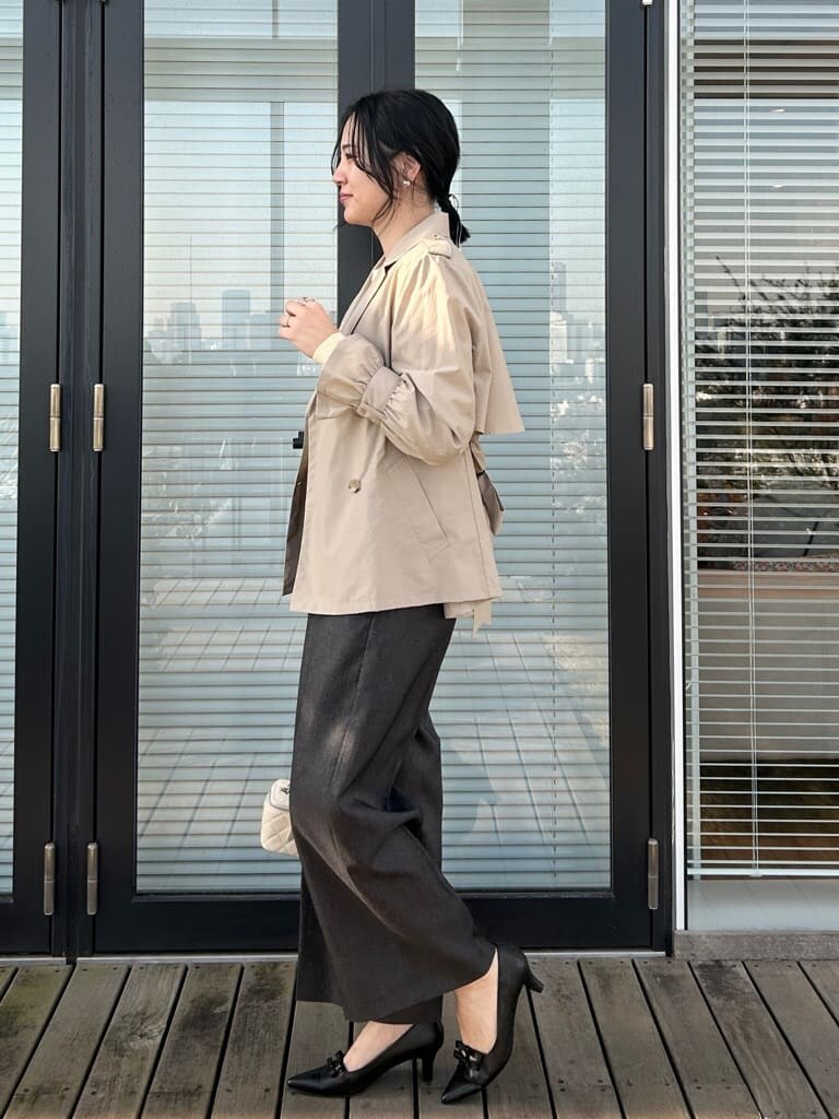 ベージュ系のトレンチコート、イエロー系のニット/セーター、ブラック系のその他パンツを着用したレディースの春コーディネートの2枚目の写真