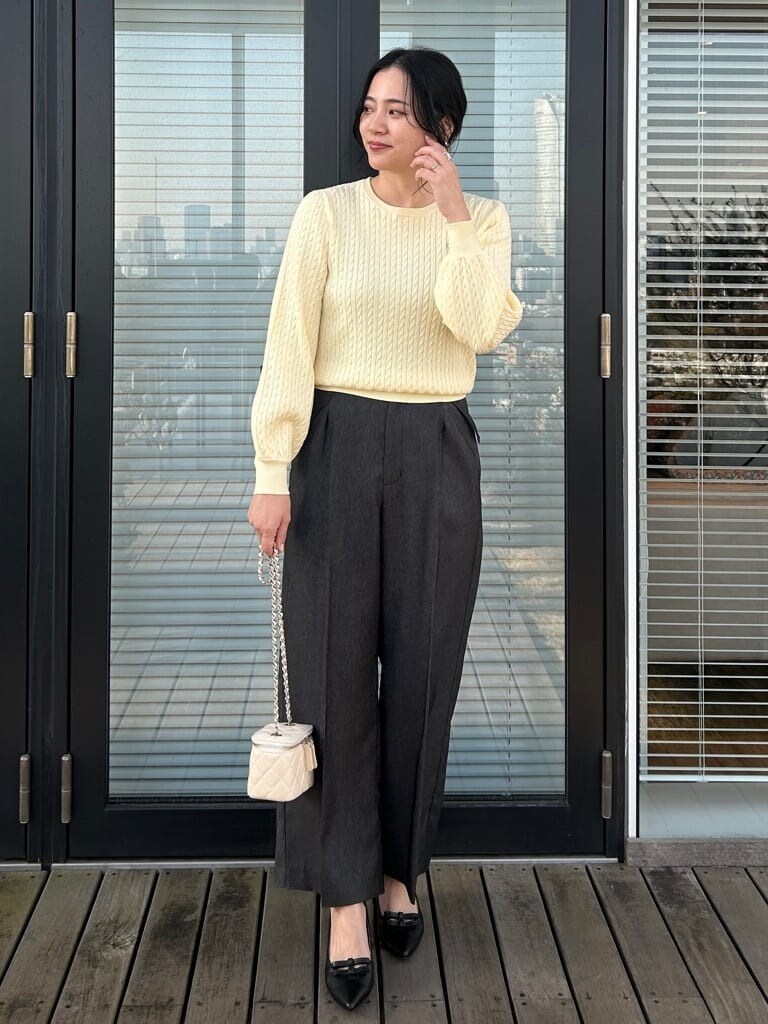 ベージュ系のトレンチコート、イエロー系のニット/セーター、ブラック系のその他パンツを着用したレディースの春コーディネートの4枚目の写真
