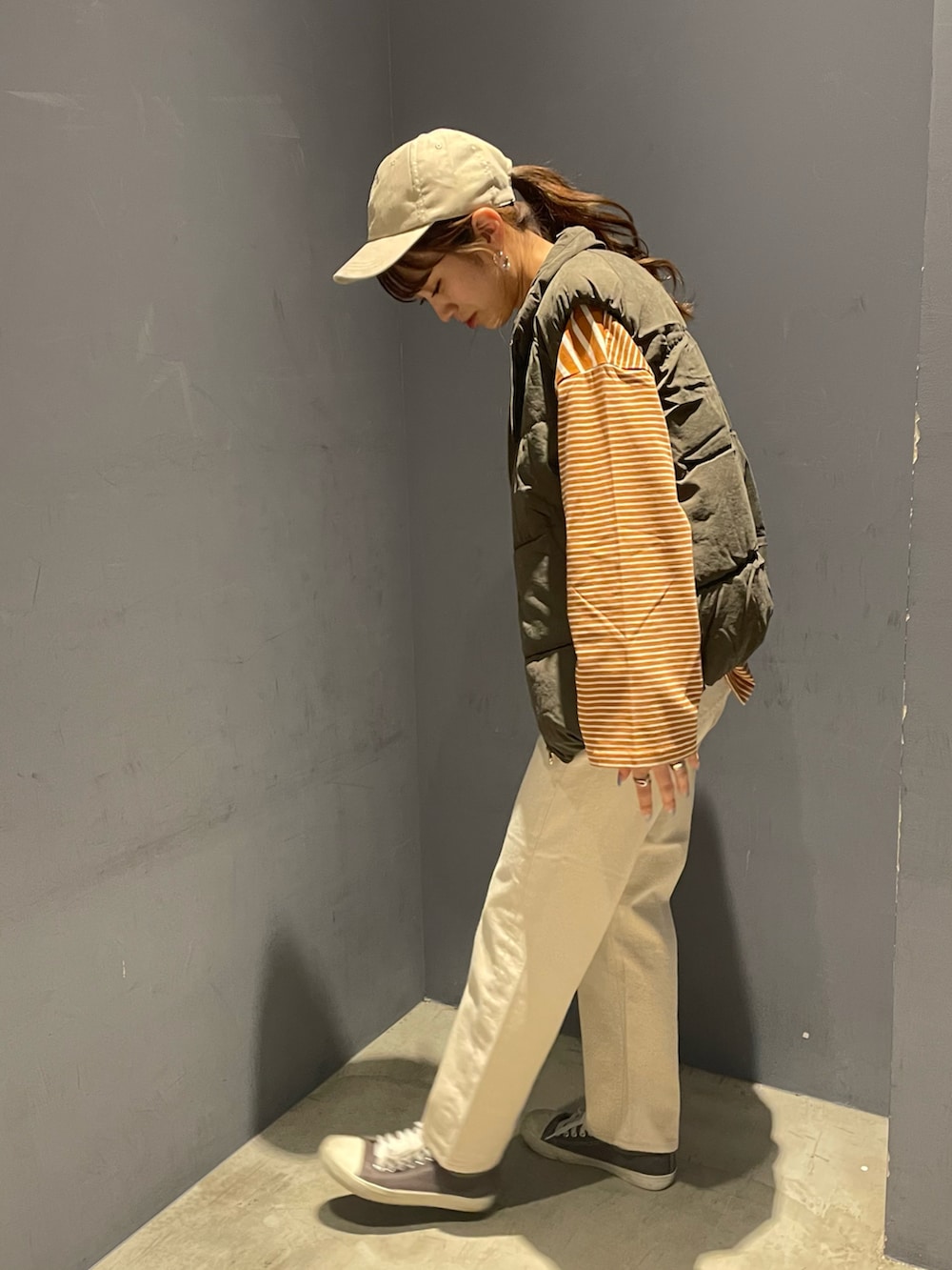 ベージュ系のデニムパンツ、グレー系のダウンベスト、オレンジ系のTシャツ/カットソーを着用したレディースの秋コーディネートの2枚目の写真