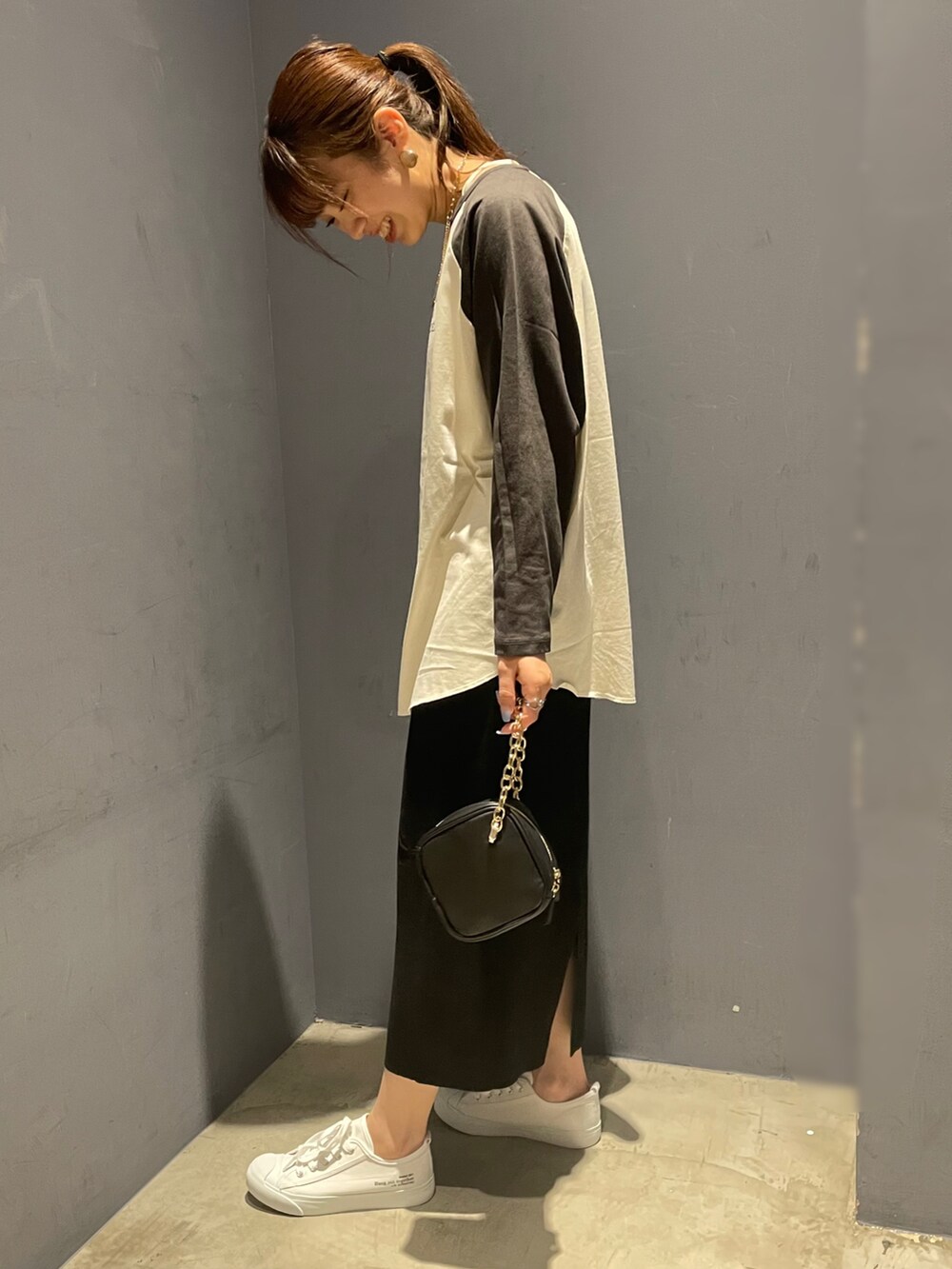 グレー系のTシャツ/カットソー、ブラック系のスカート、ブラック系のハンドバッグを着用したレディースの秋コーディネートの2枚目の写真