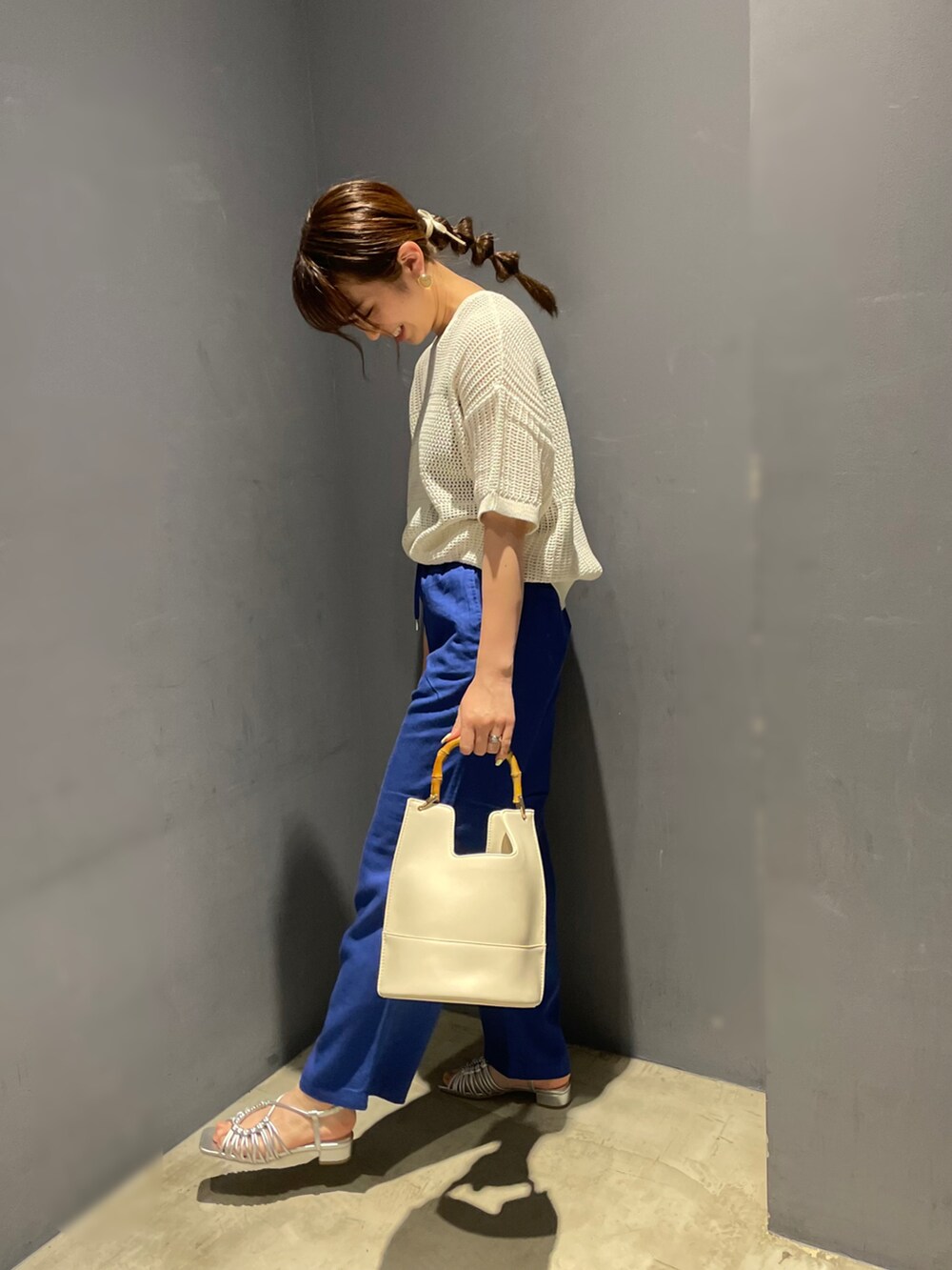 ホワイト系のニット/セーター、ブルー系のその他パンツ、ホワイト系のハンドバッグを着用したレディースの春コーディネートの2枚目の写真