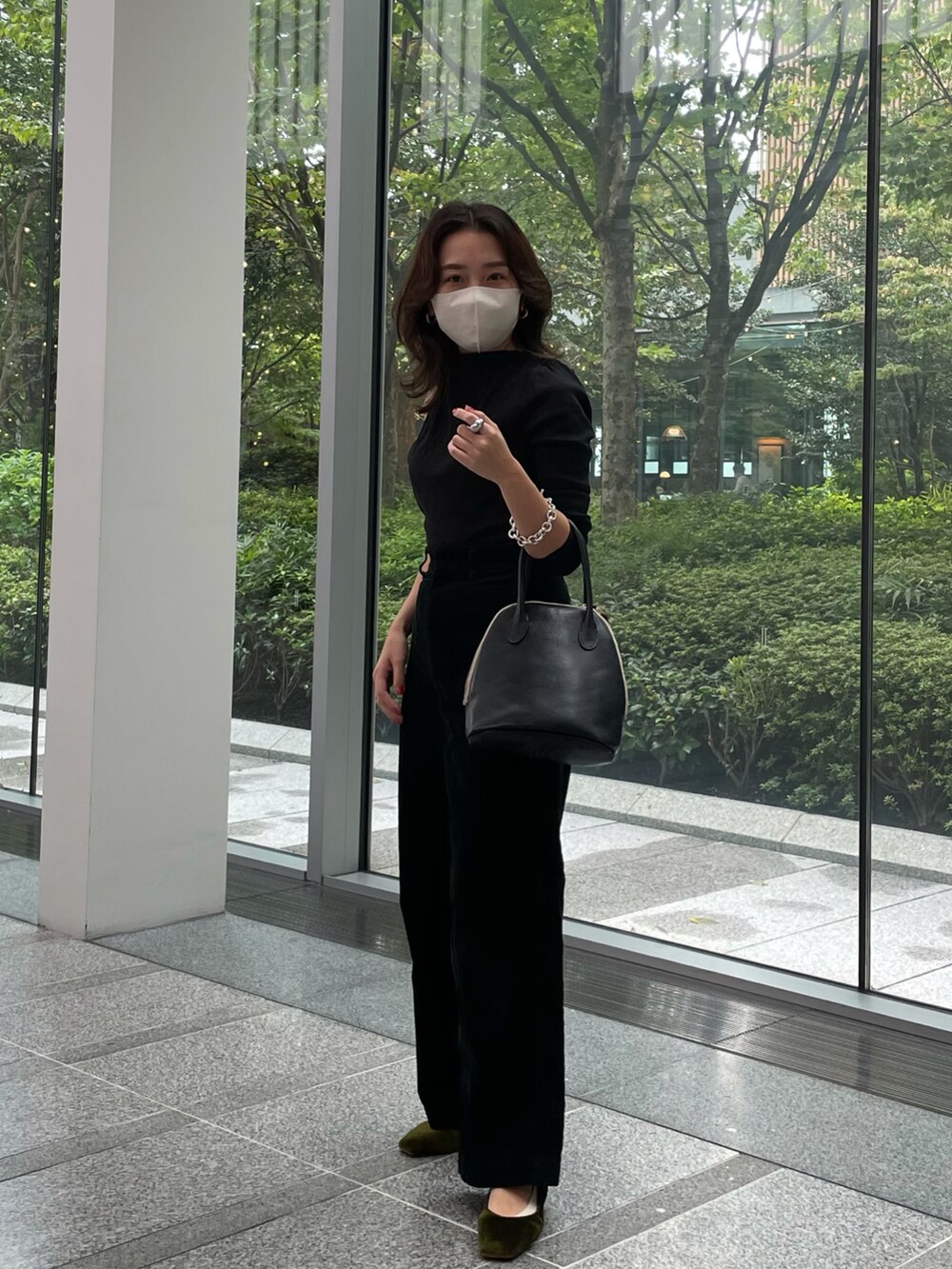 ブラック系のトップス、グリーン系のその他パンツ、ブラック系のハンドバッグを着用したレディースの秋コーディネートの2枚目の写真