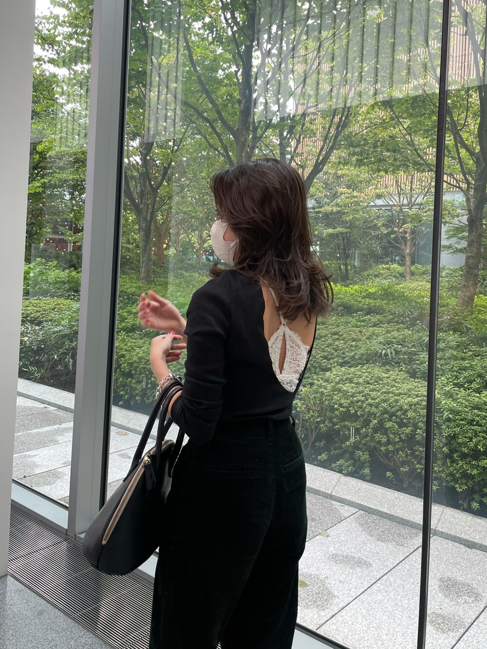 ブラック系のトップス、グリーン系のその他パンツ、ブラック系のハンドバッグを着用したレディースの秋コーディネートの5枚目の写真