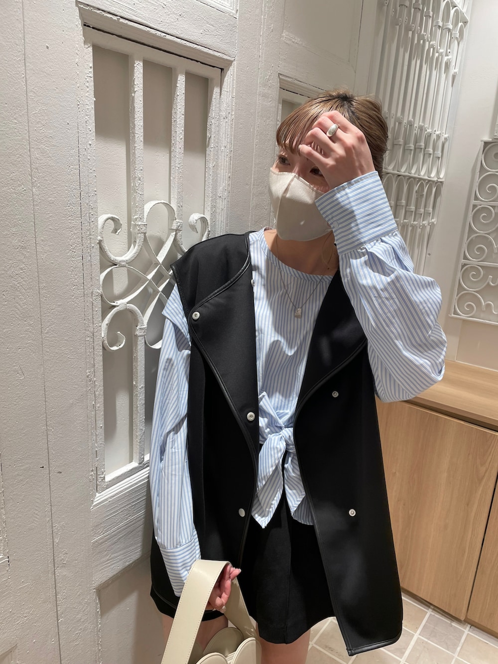 ブラック系のベスト、ブルー系のシャツ/ブラウス、グレー系のショルダーバッグを着用したレディースの春コーディネートの2枚目の写真