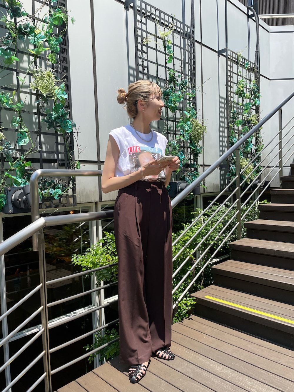 ブラック系のサンダル、ブラウン系のスラックス、ホワイト系のTシャツ/カットソーを着用したレディースの夏コーディネートの2枚目の写真