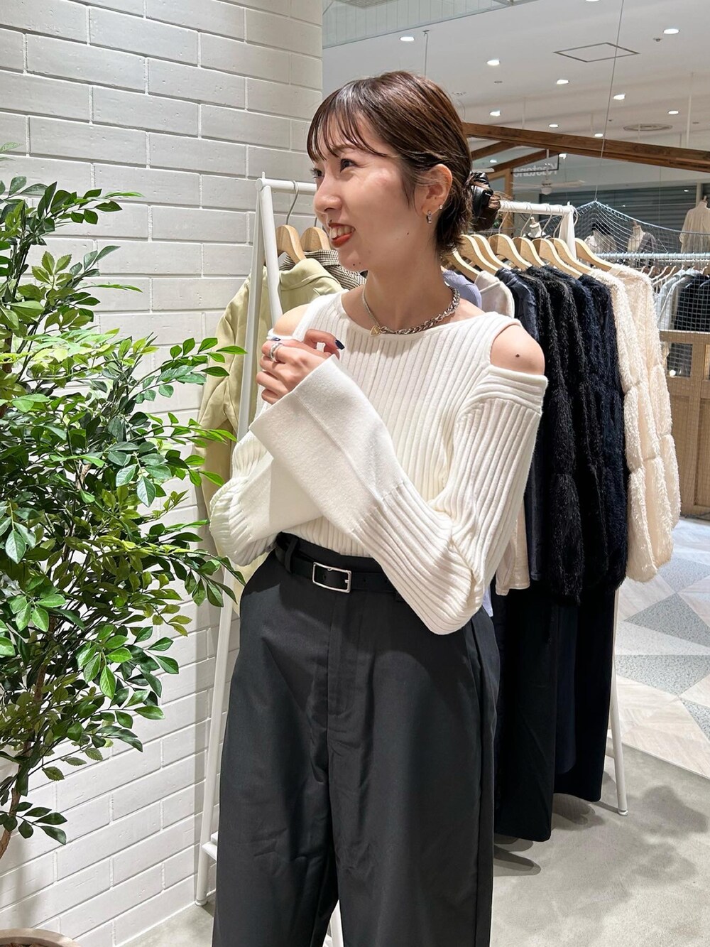 ブラック系のブーツ、グレー系のスラックス、ホワイト系のニット/セーターを着用したレディースの秋コーディネートの2枚目の写真