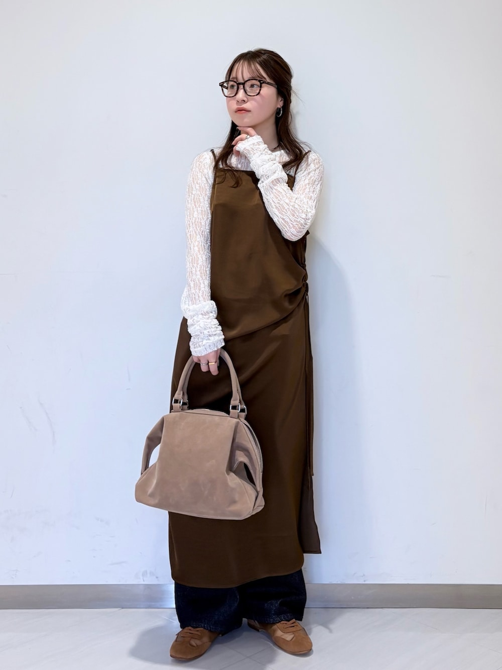 ホワイト系のTシャツ/カットソー、ブラウン系のワンピース、ブルー系のデニムパンツを着用したレディースの冬コーディネートの3枚目の写真