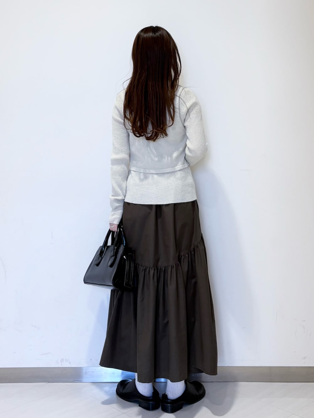 ブラック系のその他シューズ、ブラック系のボストンバッグ、グリーン系のスカートを着用したレディースの冬コーディネートの3枚目の写真