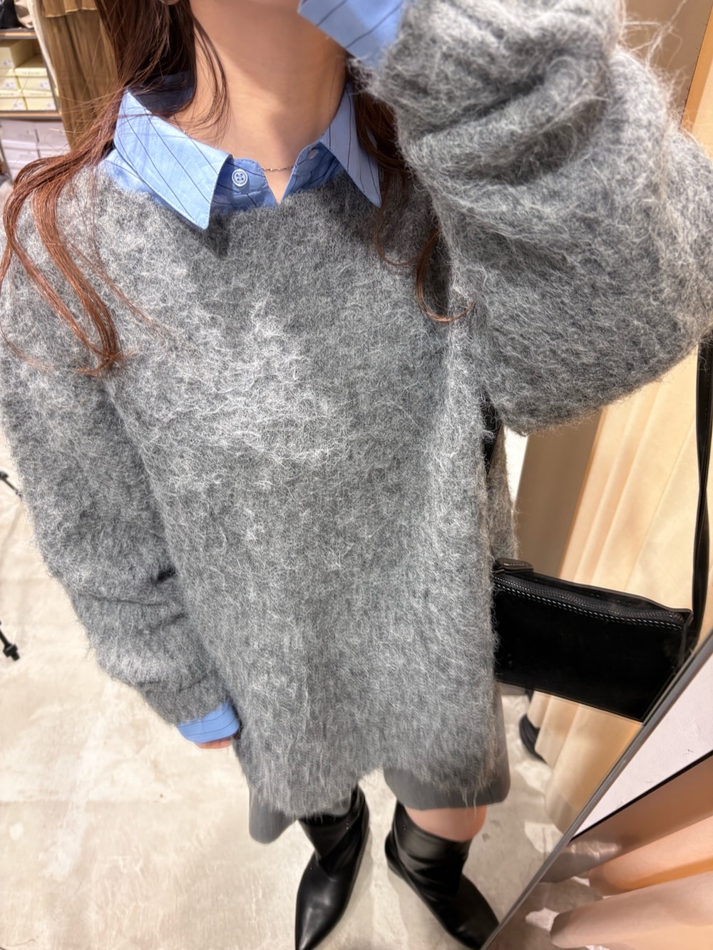 ブルー系のシャツ/ブラウス、グレー系のニット/セーター、ブラック系のショルダーバッグを着用したレディースの冬コーディネートの5枚目の写真