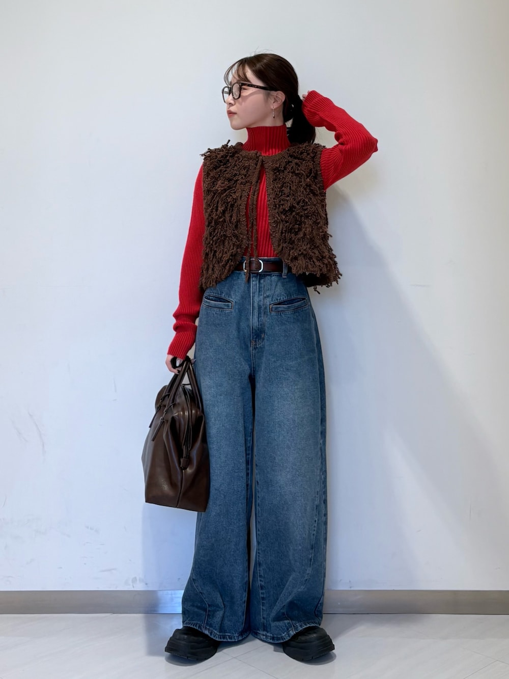 レッド系のニット/セーター、ブラウン系のベスト、ブルー系のデニムパンツを着用したレディースの冬コーディネートの4枚目の写真