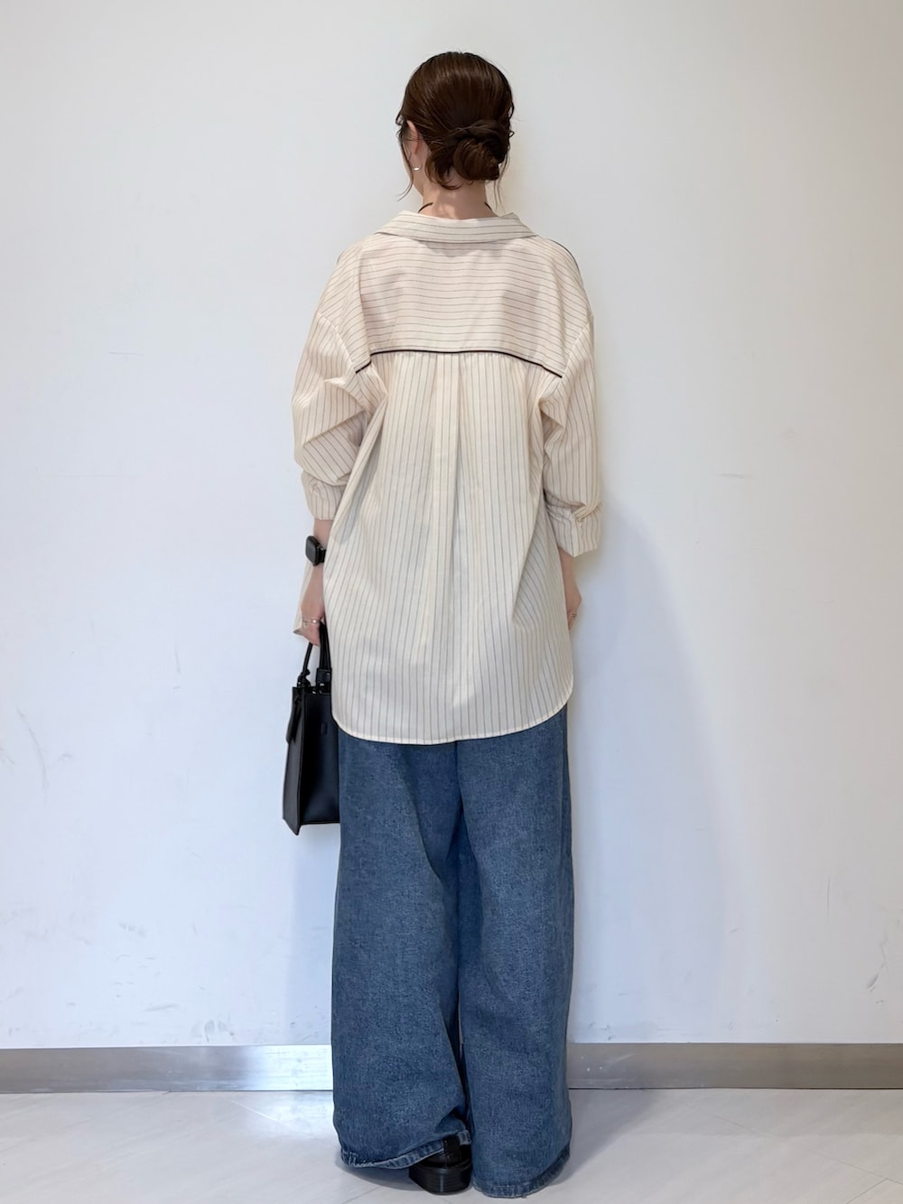 ブルー系のデニムパンツ、ブラック系のハンドバッグ、ホワイト系のキャミソールを着用したレディースの春コーディネートの3枚目の写真