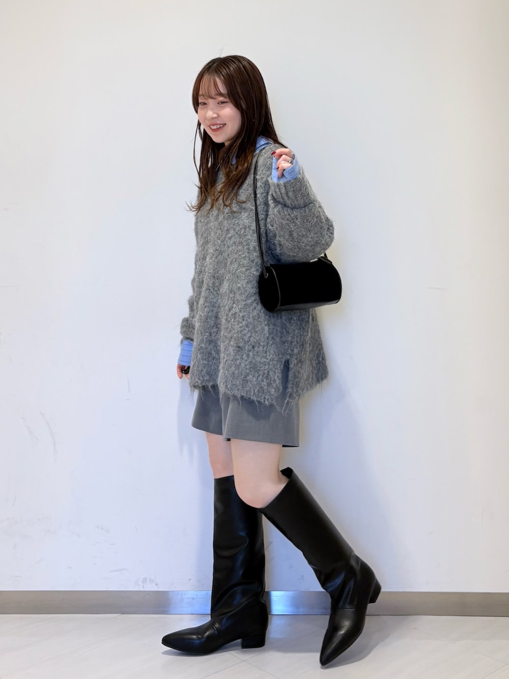 ブルー系のシャツ/ブラウス、グレー系のニット/セーター、ブラック系のショルダーバッグを着用したレディースの冬コーディネートの3枚目の写真