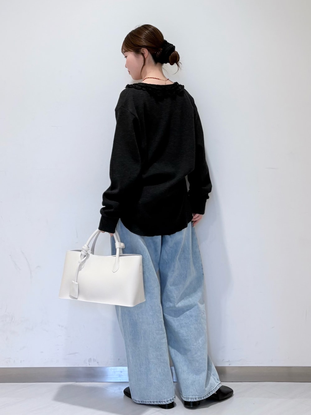 ブラック系のパンプス、ホワイト系のハンドバッグ、ブルー系のデニムパンツを着用したレディースの春コーディネートの3枚目の写真