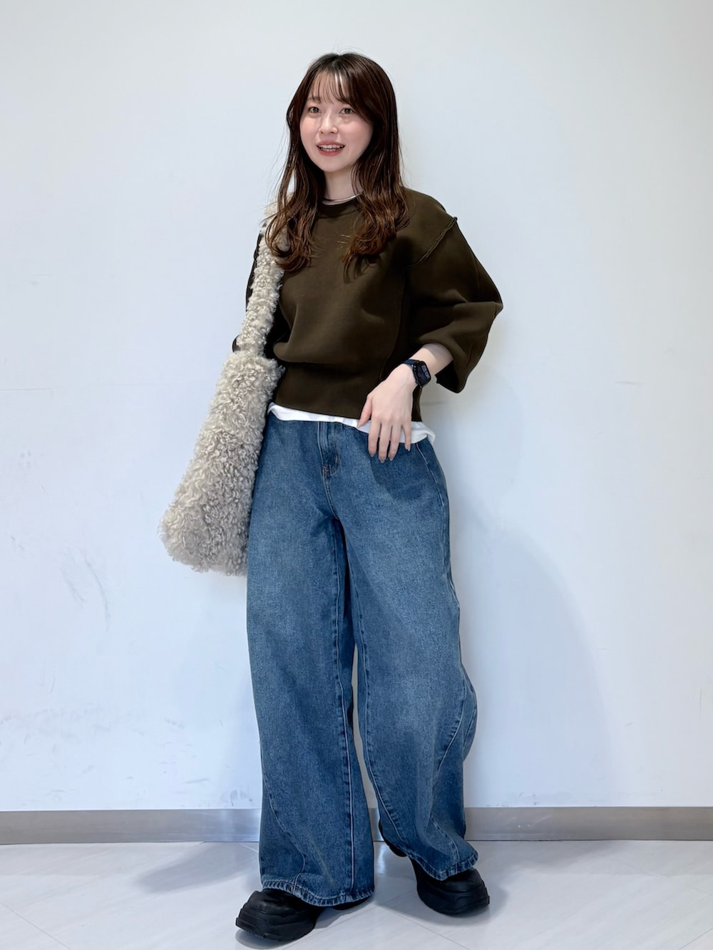 グリーン系のニット/セーター、ホワイト系のTシャツ/カットソー、ブルー系のデニムパンツを着用したレディースの秋コーディネートの4枚目の写真