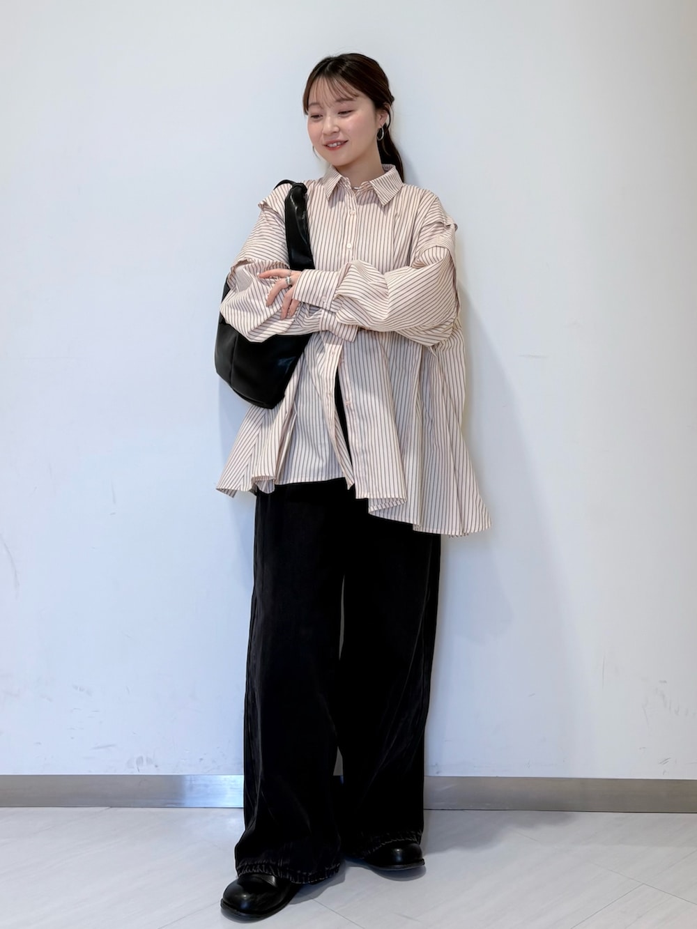 ピンク系のシャツ/ブラウス、ブラック系のショルダーバッグ、ブラック系のデニムパンツを着用したレディースの冬コーディネートの2枚目の写真