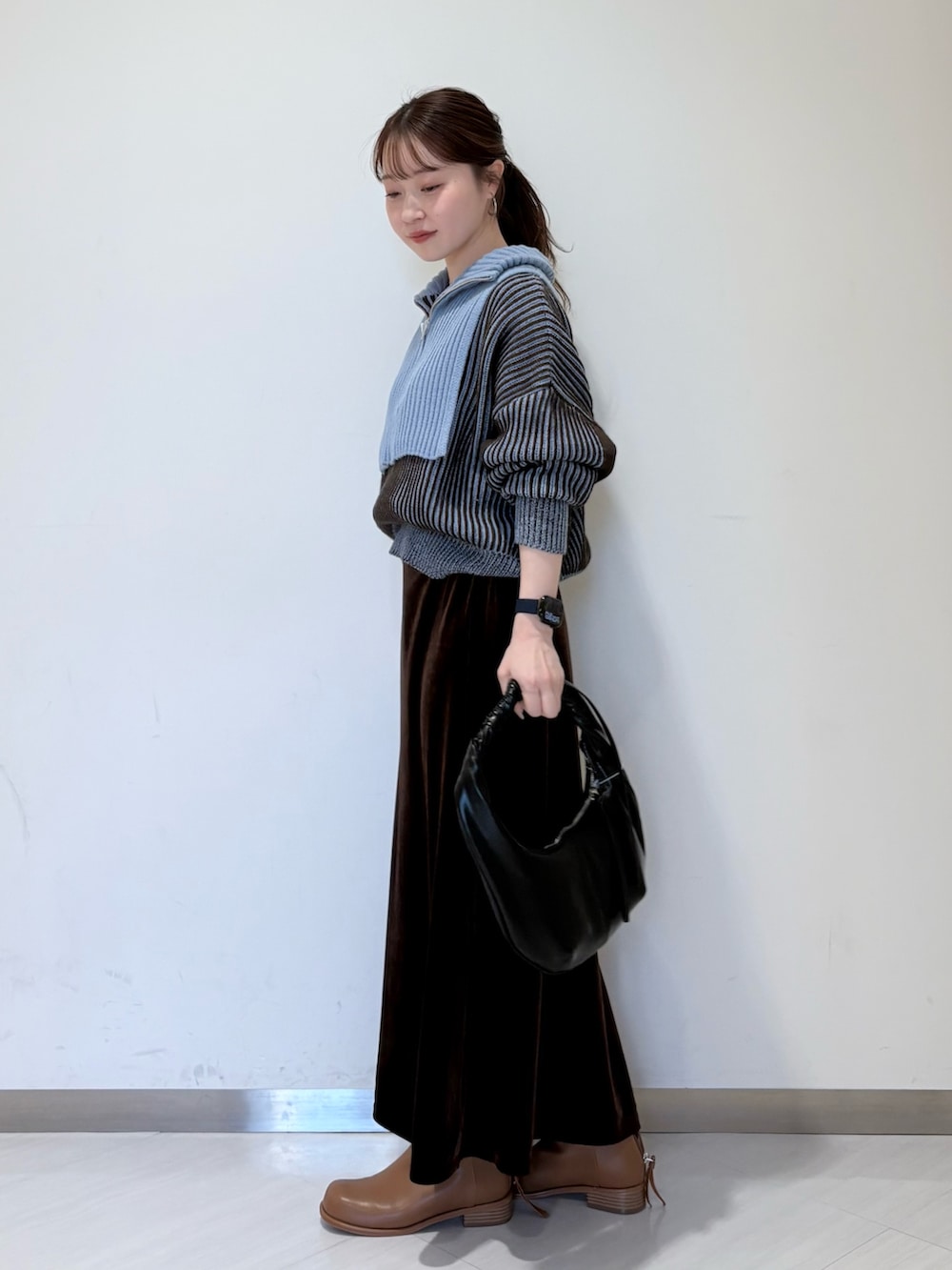ブルー系のニット/セーター、ブラウン系のスカート、ブラウン系のブーツを着用したレディースの秋コーディネートの4枚目の写真