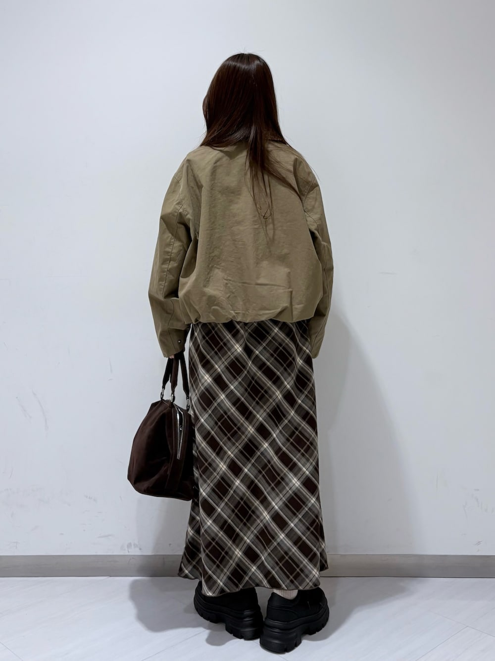 グリーン系のブルゾン、ブラウン系のスカート、ブラック系のスニーカーを着用したレディースの冬コーディネートの2枚目の写真