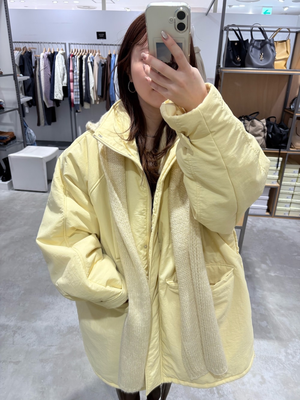 イエロー系のダウンジャケット/コート、イエロー系のボストンバッグ、ブラウン系のブーツを着用したレディースの秋コーディネートの4枚目の写真