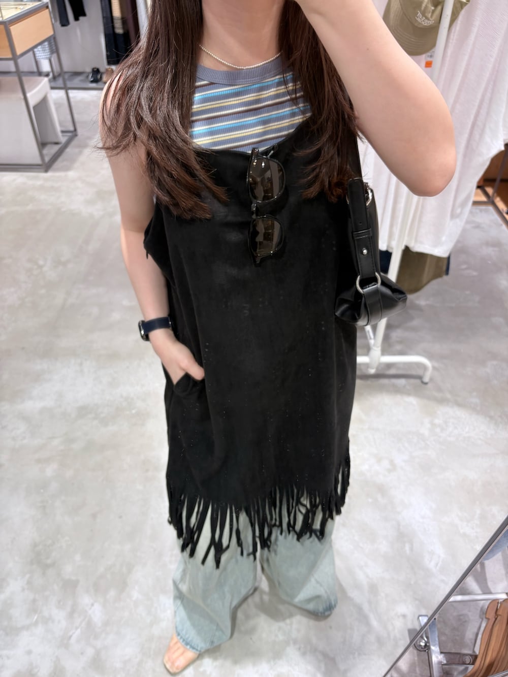 ブルー系のデニムパンツ、ブラック系のショルダーバッグ、ブルー系のタンクトップを着用したレディースの夏コーディネートの4枚目の写真