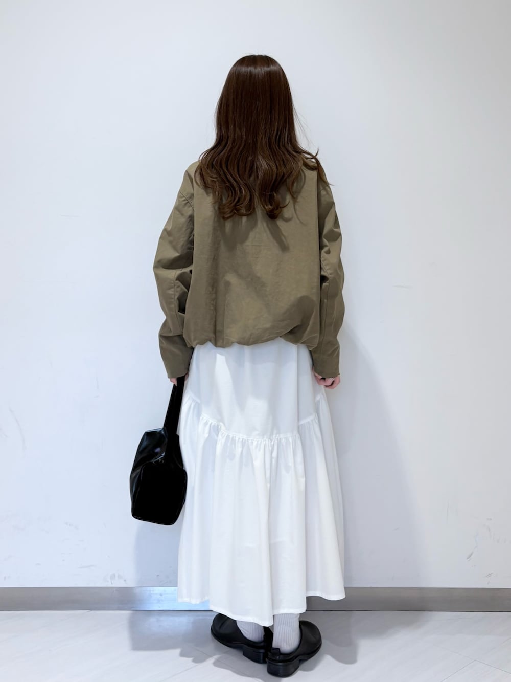 グリーン系のブルゾン、ブラック系のその他シューズ、ホワイト系のスカートを着用したレディースの春コーディネートの2枚目の写真