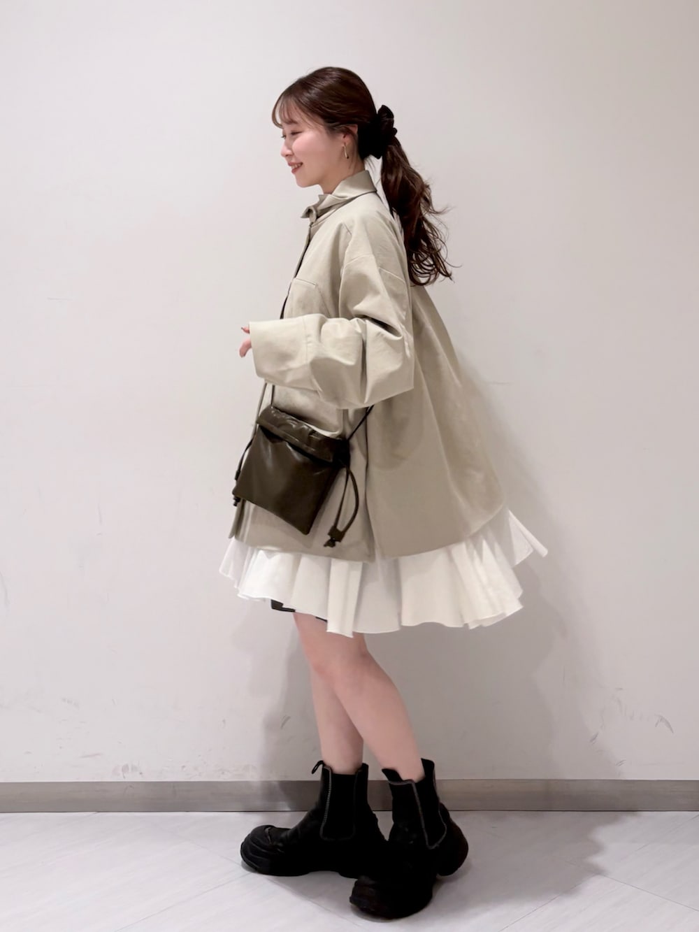 グリーン系のショルダーバッグ、ベージュ系のその他アウター、ホワイト系のワンピースを着用したレディースの春コーディネートの2枚目の写真