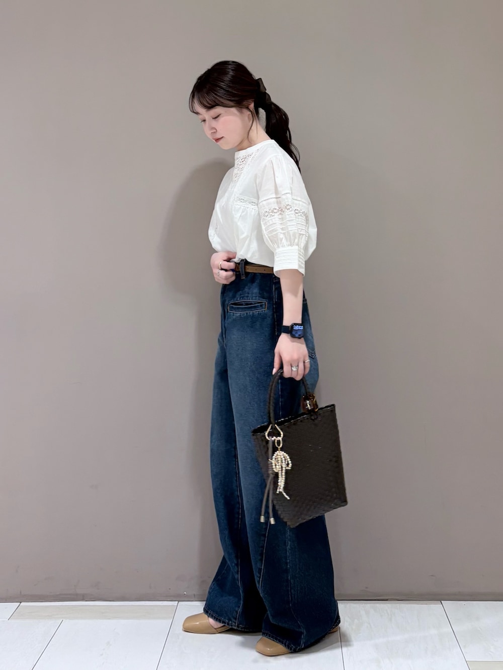 イエロー系のパンプス、ブラウン系のトートバッグ、ブルー系のデニムパンツを着用したレディースの春コーディネートの2枚目の写真