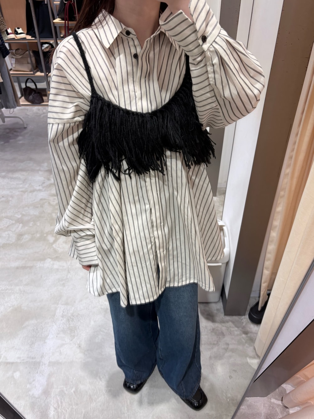 ブラック系のニット/セーター、ブルー系のデニムパンツ、ブラック系のハンドバッグを着用したレディースの夏コーディネートの5枚目の写真