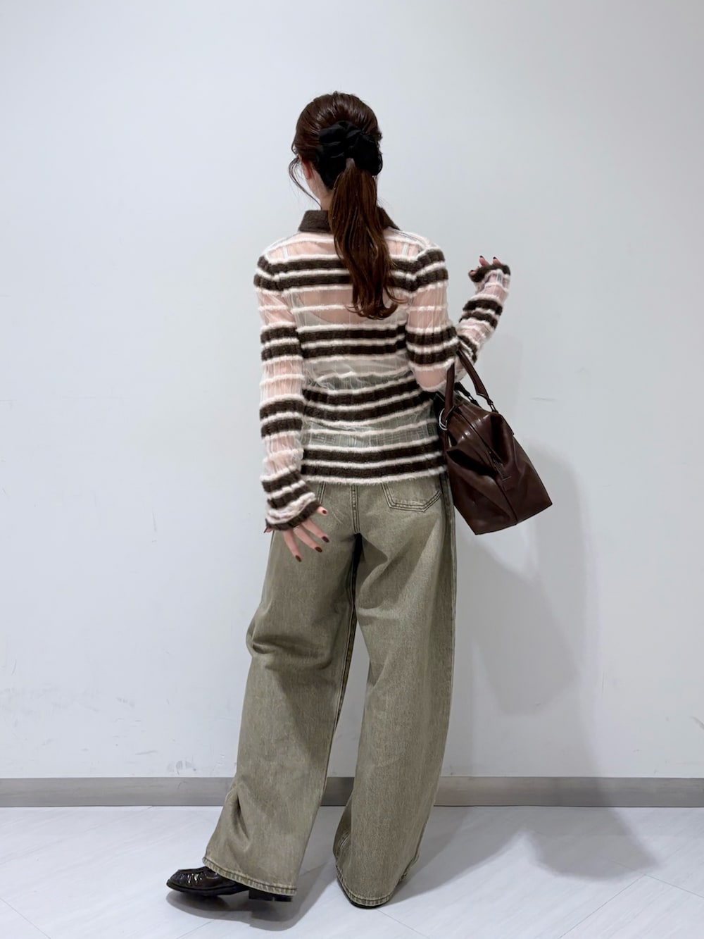 ブラウン系のニット/セーター、グリーン系のデニムパンツ、ブラウン系のボストンバッグを着用したレディースの秋コーディネートの3枚目の写真