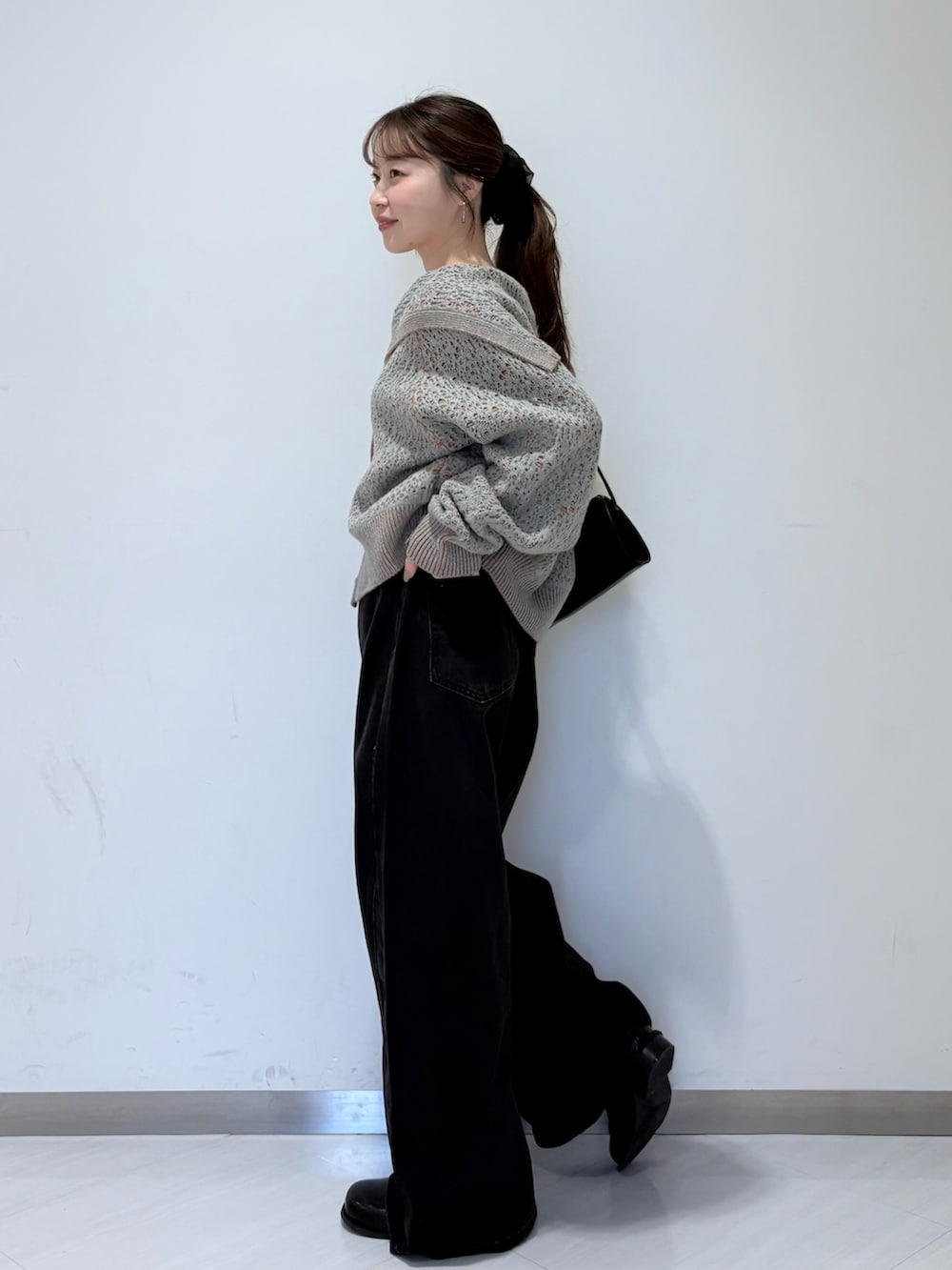 グレー系のニット/セーター、ブラック系のその他シューズ、ブラック系のデニムパンツを着用したレディースの秋コーディネートの2枚目の写真