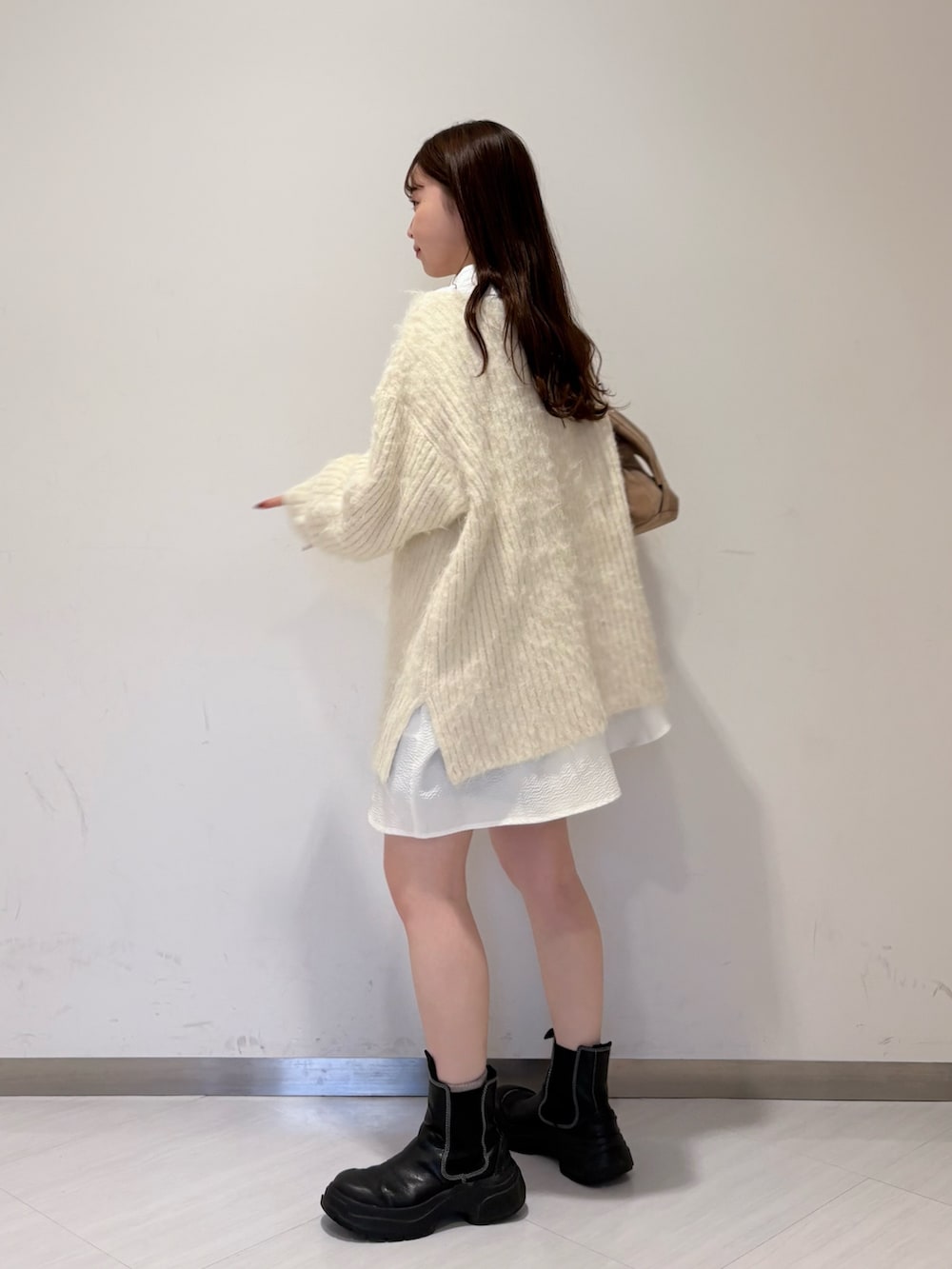 ホワイト系のニット/セーター、ベージュ系のボストンバッグ、ホワイト系のシャツ/ブラウスを着用したレディースの冬コーディネートの2枚目の写真