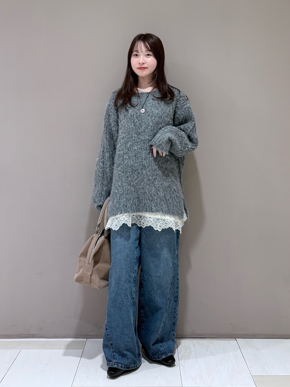 グレー系のニット/セーター、ブラック系のパンプス、ホワイト系のキャミソールを着用したレディースの冬コーディネートの2枚目の写真