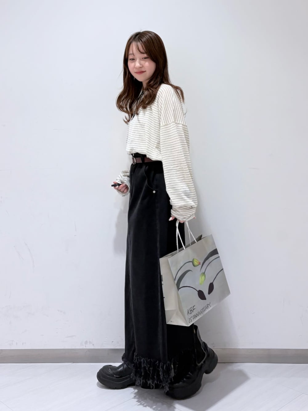 ホワイト系のニット/セーター、ブラック系のスカート、ブラウン系のベルトを着用したレディースの冬コーディネートの2枚目の写真