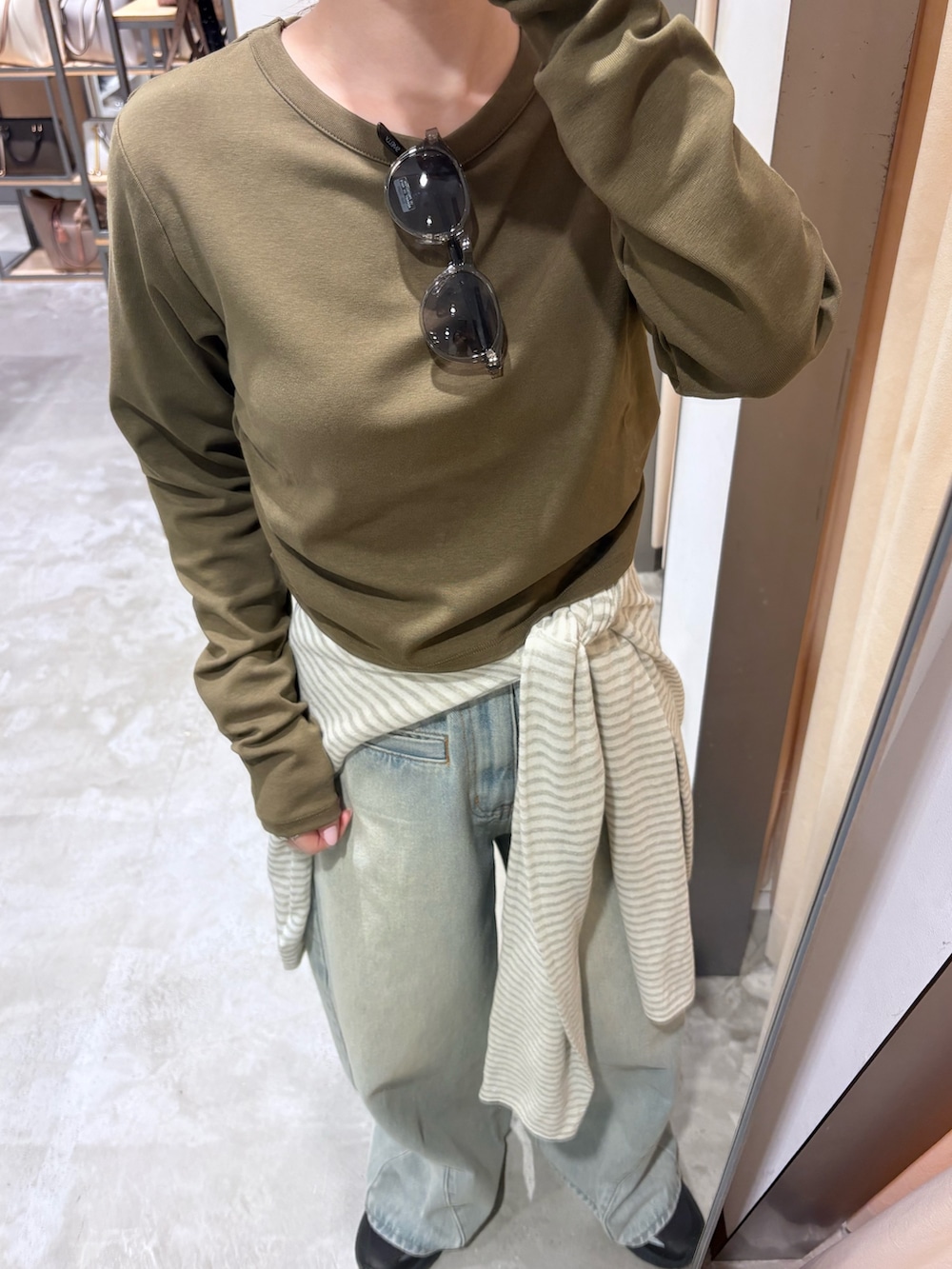 グリーン系のTシャツ/カットソー、ホワイト系のニット/セーター、ブラック系のハンドバッグを着用したレディースの春コーディネートの5枚目の写真