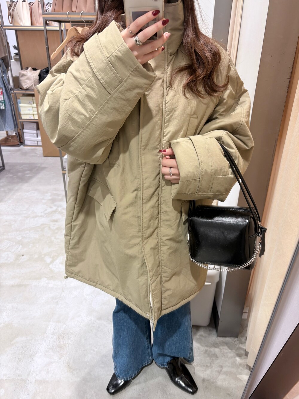 グリーン系のダウンジャケット/コート、ブルー系のデニムパンツ、ブラック系のパンプスを着用したレディースの冬コーディネートの5枚目の写真